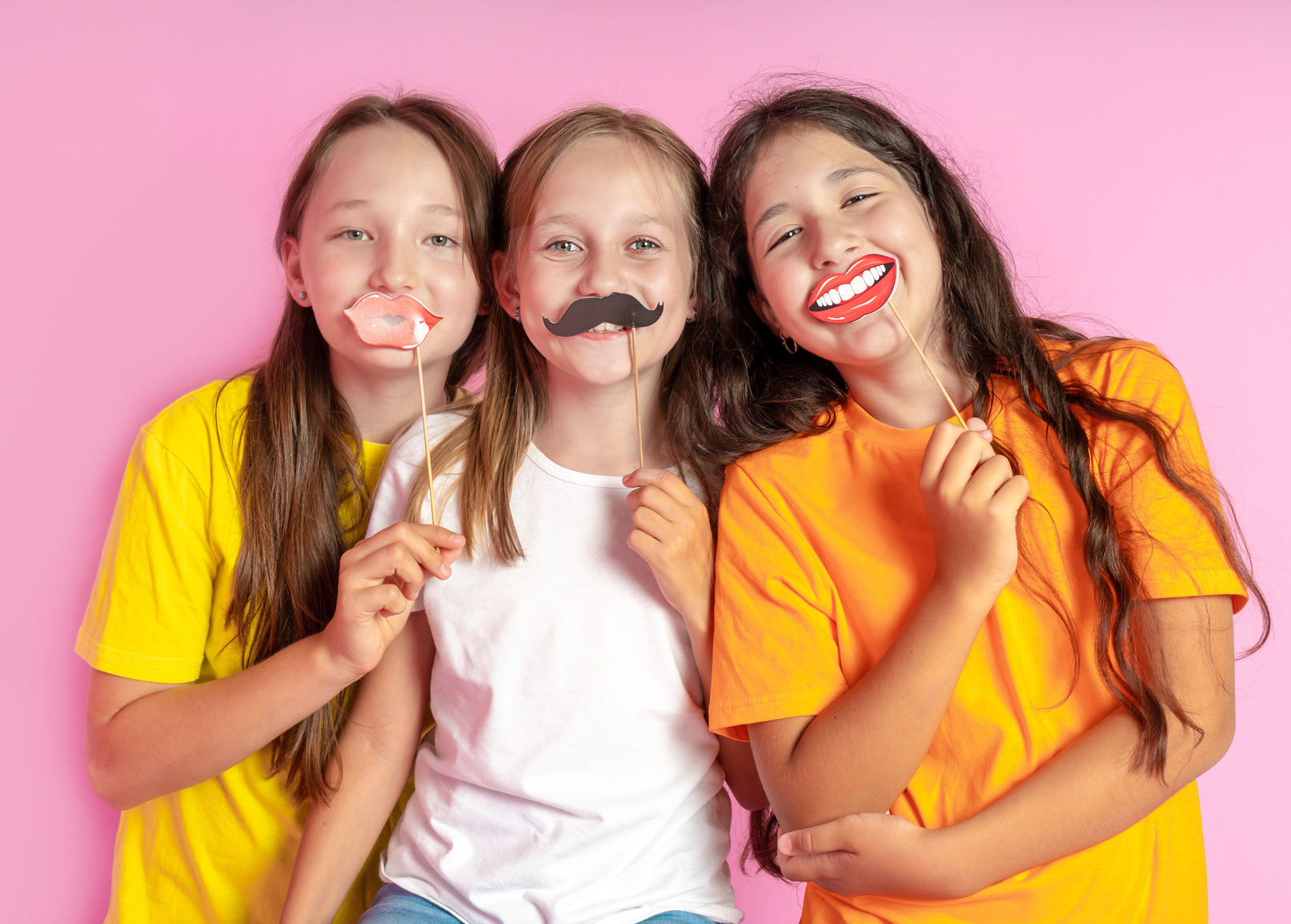Happy Children hold fake mustache and lips on a pink background. Beauty salon.  Hair design salon. Salon photobooth.